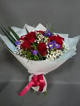 Фото флориста 4: Букет из 9 красных роз и 6 синих ирисов в бумаге с зеленью