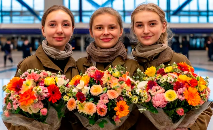 Встречающие стоят с букетами цветов в аэропорту